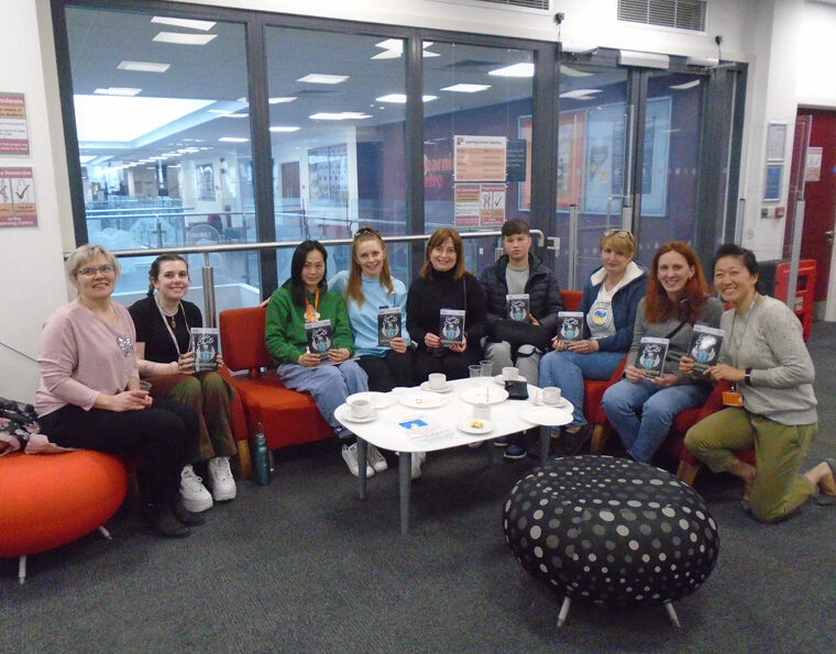 Group of students holding copies of the book, sitting around a table.