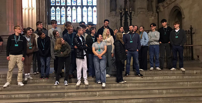 Students get a group photograph taken. They are looking at their teacher instead of the camera.