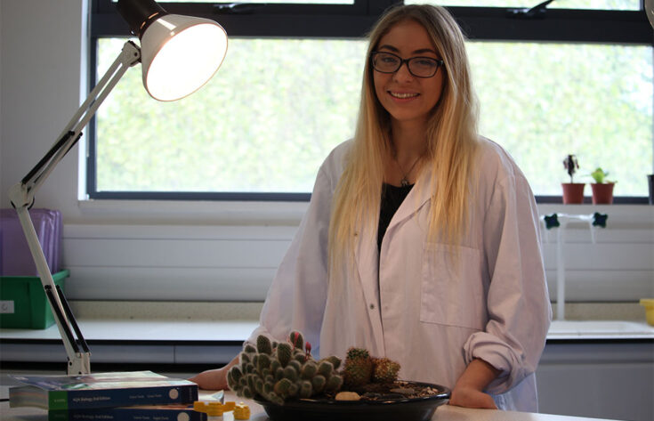 Photograph of a biology student with books and some plants.