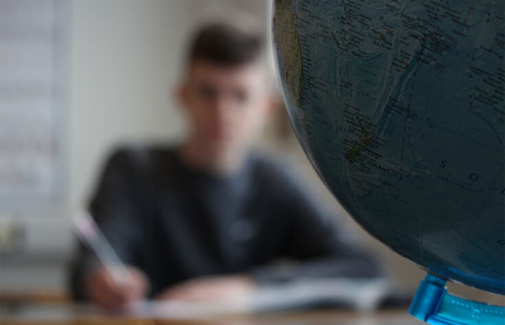 Photograph of a student studying Geography next to a globe