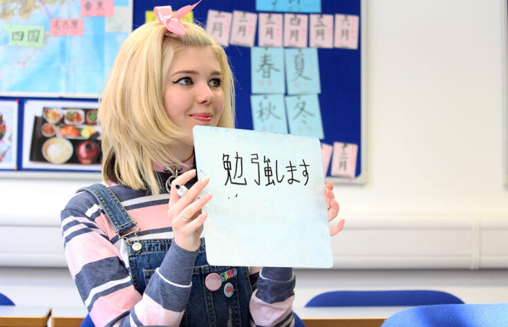 Photograph of a Japanese student holding up a card