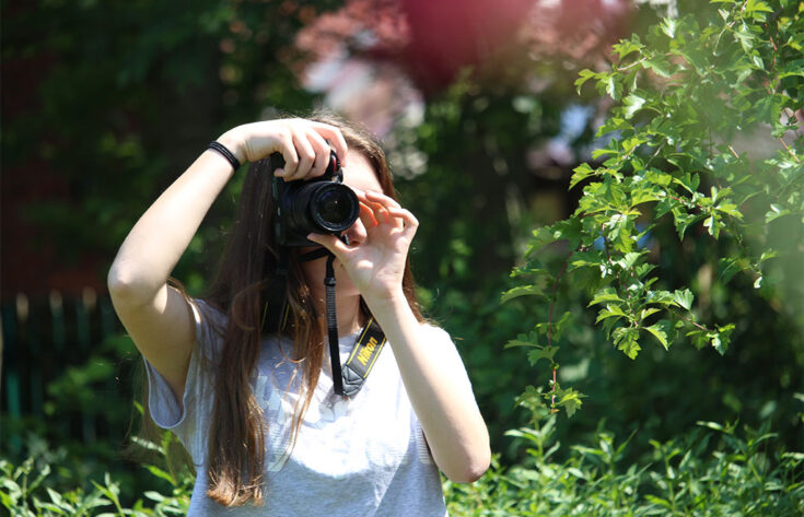 Photograph of a photography student taking a photograph outdoors.