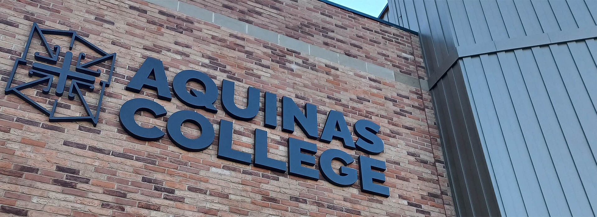 Photograph of the new building showing the Aquinas logo