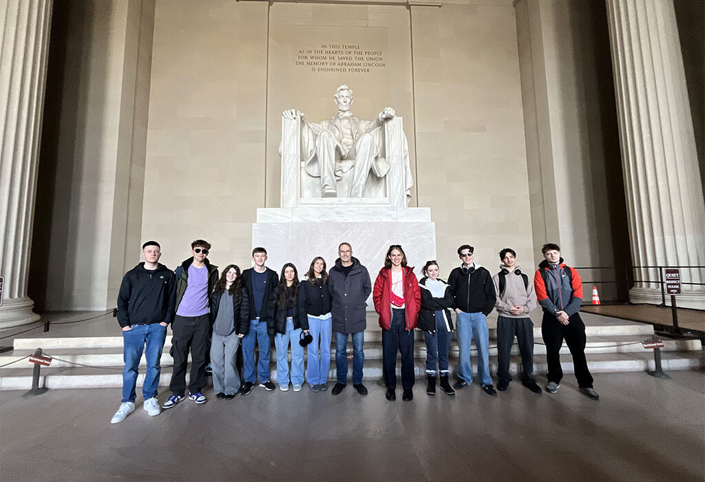 Photograph of a group of students stood next to a statue